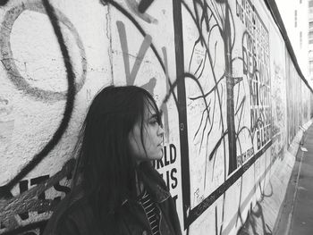 Young woman leaning in graffiti wall
