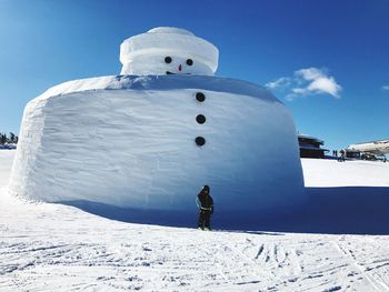 Full length of boy standing on snow covered field against built structure