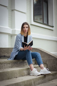 Young woman using mobile phone while sitting on staircase