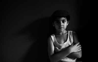 Portrait of boy standing against black background