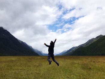 Man jumping on field against mountain range