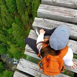 Rear view of woman sitting on wood