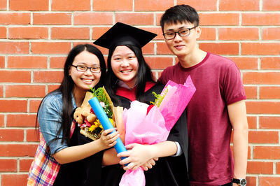 Portrait of family standing against brick wall during convocation