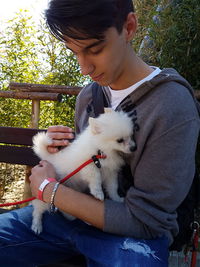 Midsection of woman with dog sitting outdoors