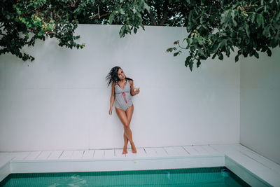 Full length of woman standing against wall