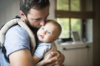 Father cuddling with baby in baby carrier