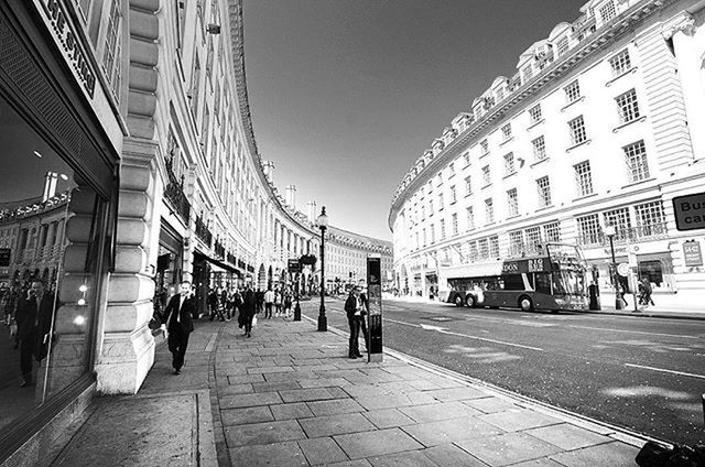 architecture, built structure, building exterior, city, large group of people, city life, street, the way forward, walking, incidental people, person, city street, men, clear sky, transportation, building, diminishing perspective, road, outdoors