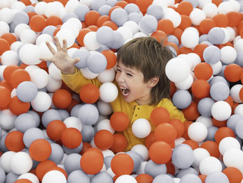 Laughing boy plays in ball pit. plastic balls in dry paddling pool. playroom at kindergarten. 