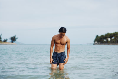 Shirtless man standing in lake