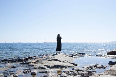 Woman standing on beach against clear sky