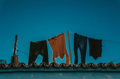 Low angle view of clothes drying against blue sky