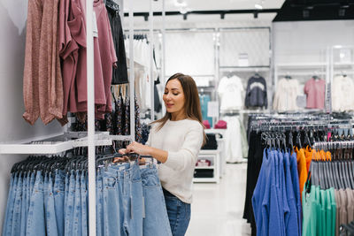 Caucasian woman chooses jeans, casual clothes in the store person