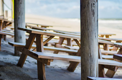 Empty chairs and table at beach against sky