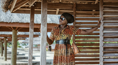 Woman wearing sunglasses standing against built structure