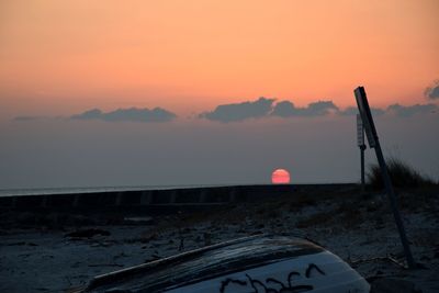 Scenic view of a beach with a boat against sky during sunset