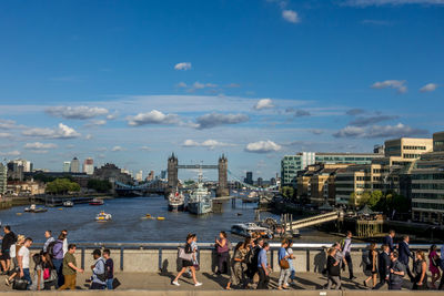 People on boats in river by city against sky