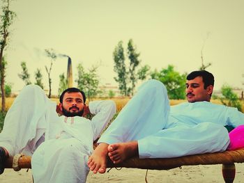 Men sitting on bed against clear sky