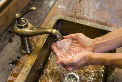 High angle view of hands under running faucet