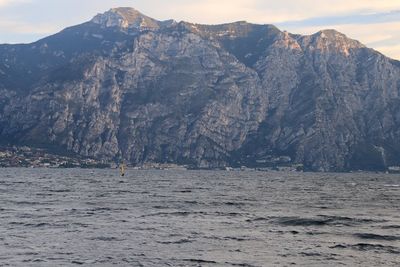 Scenic view of sea by mountains against sky