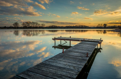 Pier on the lake, reflection of clouds in the water after sunset, eastern poland