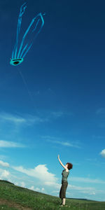 Tilt shot of woman flying kite on field