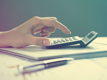 Cropped hands of businesswoman using calculator with documents at desk