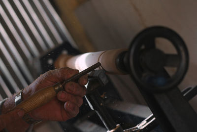 Close-up of man working wood work on lathe 