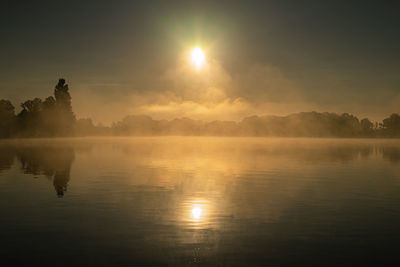 Scenic view of lake against sky during sunset foggy 