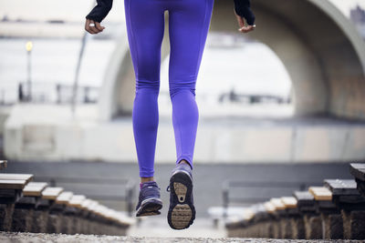 Low section of sporty woman jogging at stadium