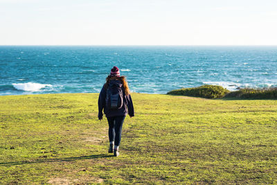 Full length rear view of man on sea shore against sky