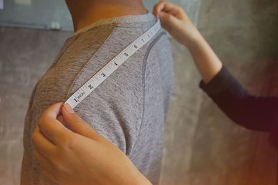 Cropped image of fashion designer taking measurement of shoulder