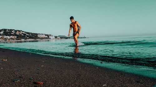 Man model coming out of the water. alone at the beach. sunset beach.