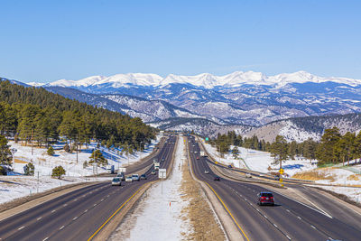 High angle view of road by snowcapped mountains against clear blue sky