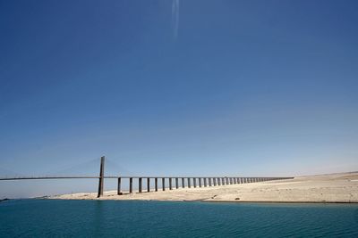 Bridge over sea against blue sky