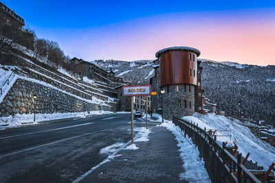 Soldeu sign at entrance to the town, pine forest and mountain range in background, andorra