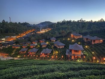 Houses on field by buildings against sky at dusk