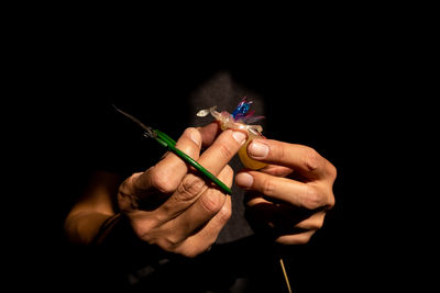 Close-up of hand holding sparkler against black background