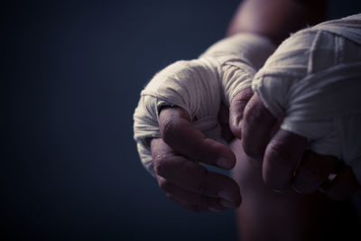Close-up of boxer hands wearing bandage against black background