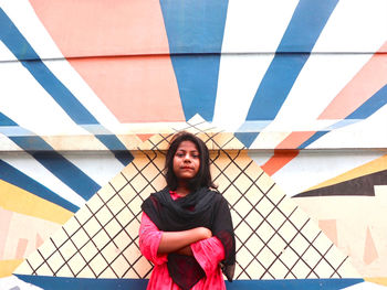 Portrait of young girl standing against wall