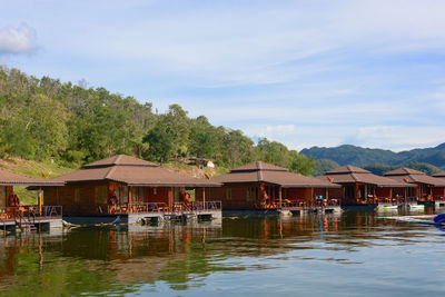 Houses by lake and buildings against sky