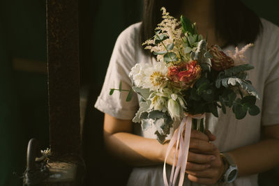 Midsection of woman holding flower bouquet