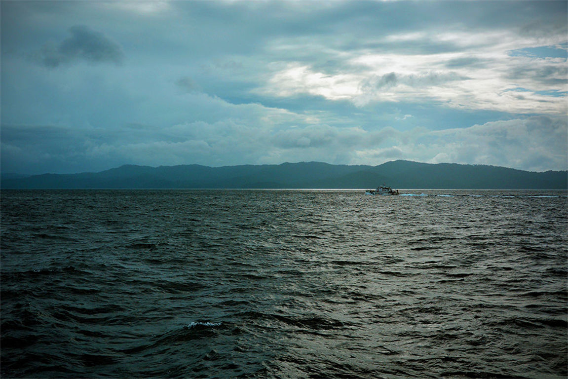 SCENIC VIEW OF SEA AGAINST MOUNTAINS