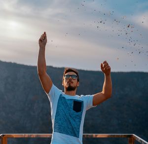 Young man standing against sky