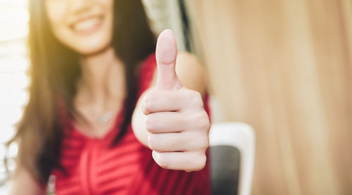 Midsection of woman gesturing thumbs up