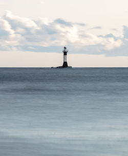 Lighthouse by sea against sky