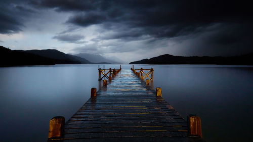 Pier over lake against sky at dusk