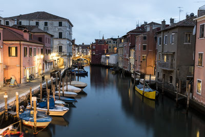 Boats moored in canal amidst buildings