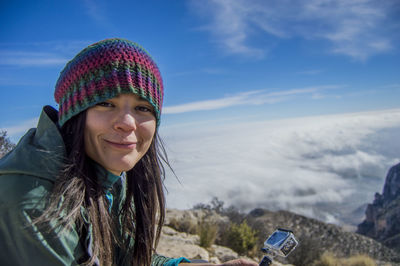 Woman sitting on rock against cloudscape