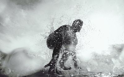 Silhouette man splashing water against sea