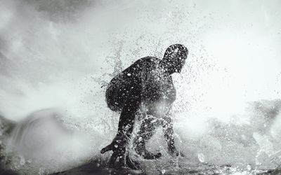 Low angle view of silhouette man in sea against sky